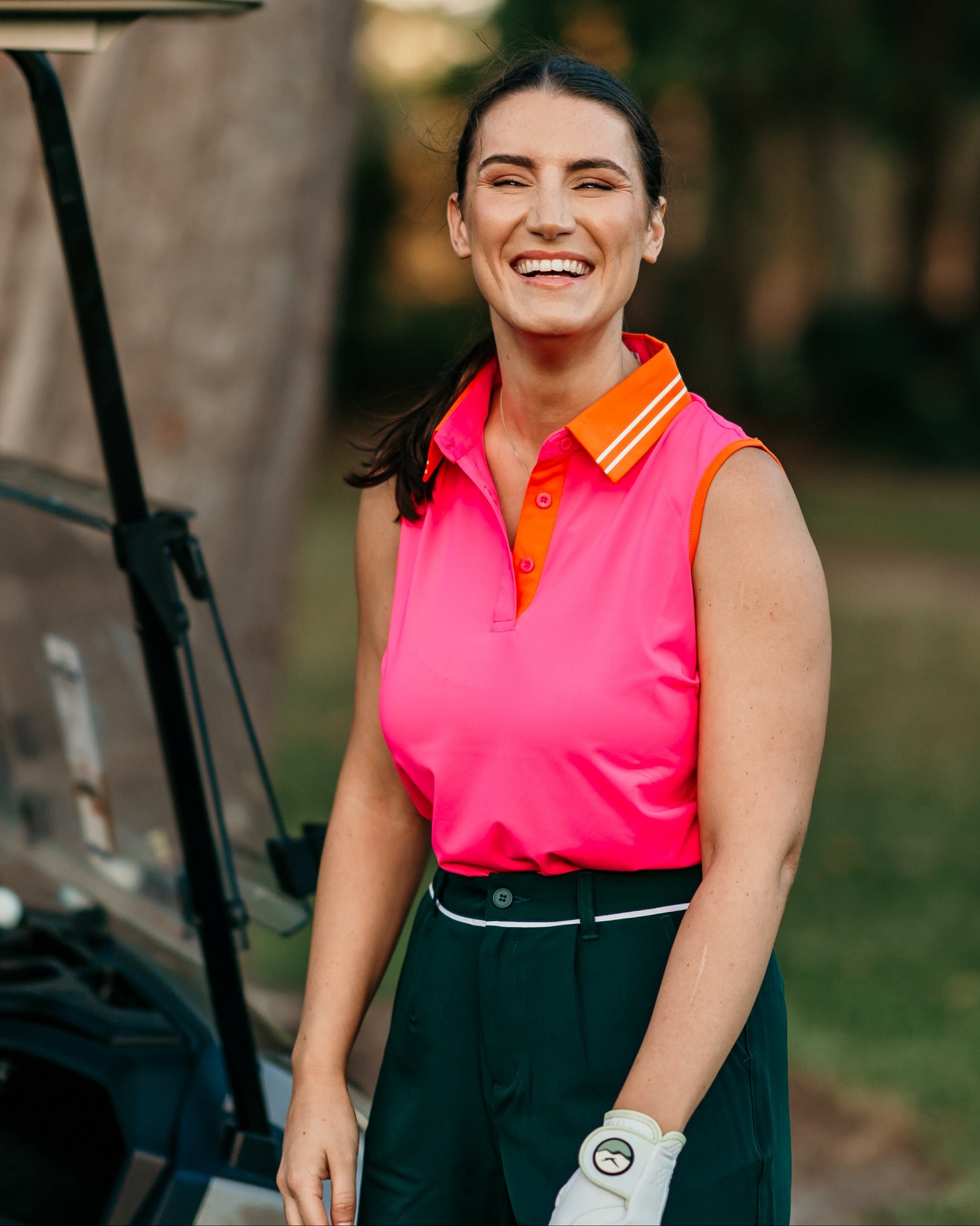 Female golfer on course wearing linksy golf margie polo, stella shorts, and the linksy glove