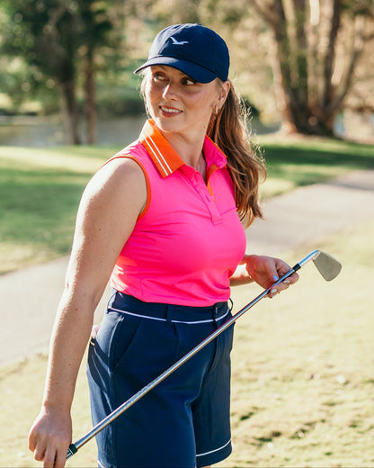 Girl golfer wears linksy gear on courser, stella shorts navy, magrie polo pink and little birdie cap navy