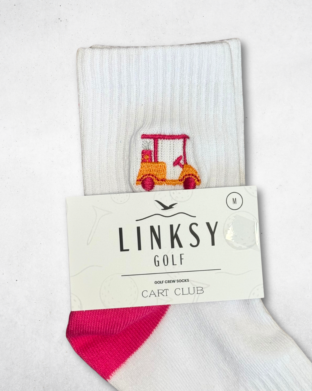 White linksy cart club crew socks in packaging with pink accents and a small logo on a light gray background