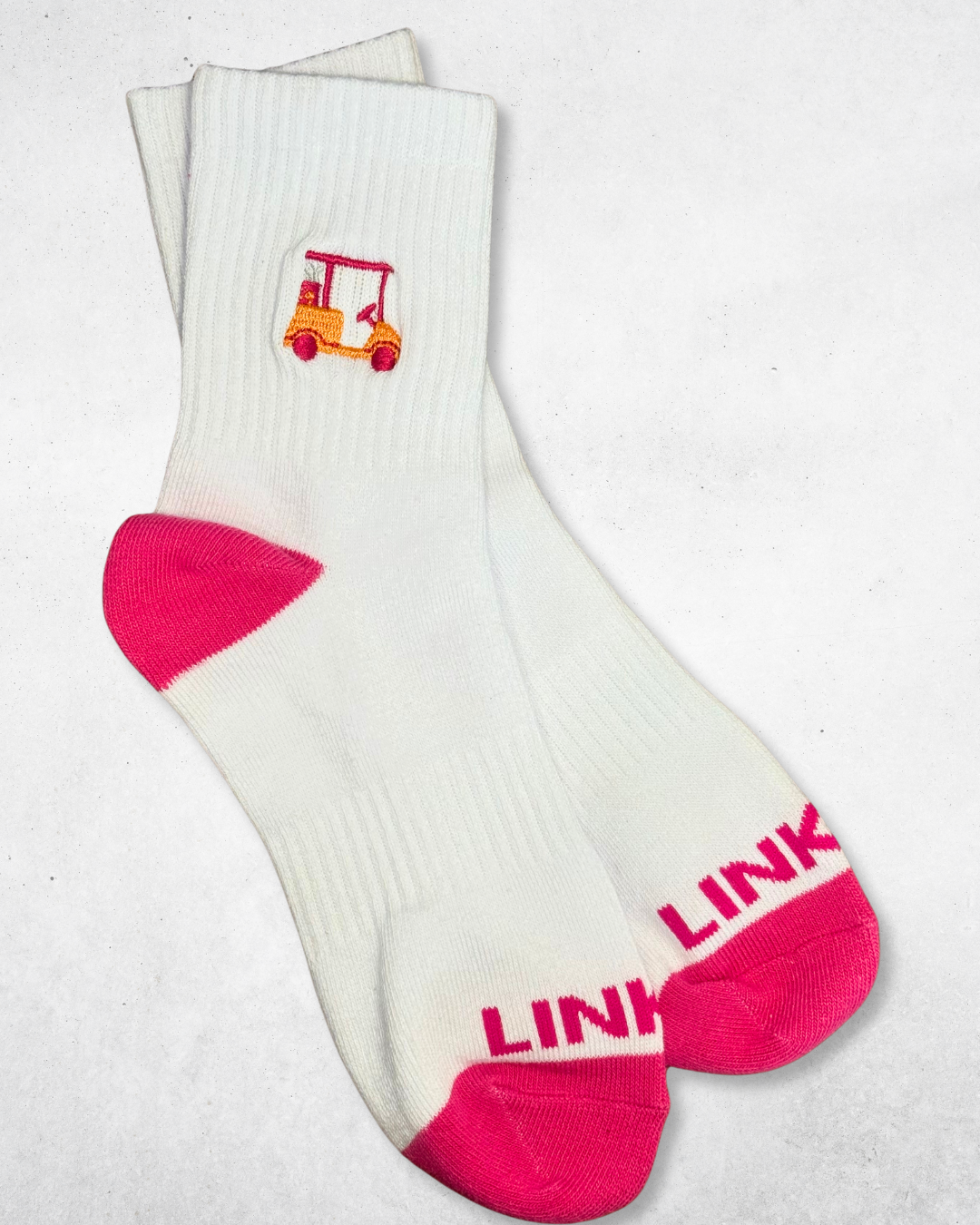White linksy cart club crew socks with pink accents and a small logo on a light gray background