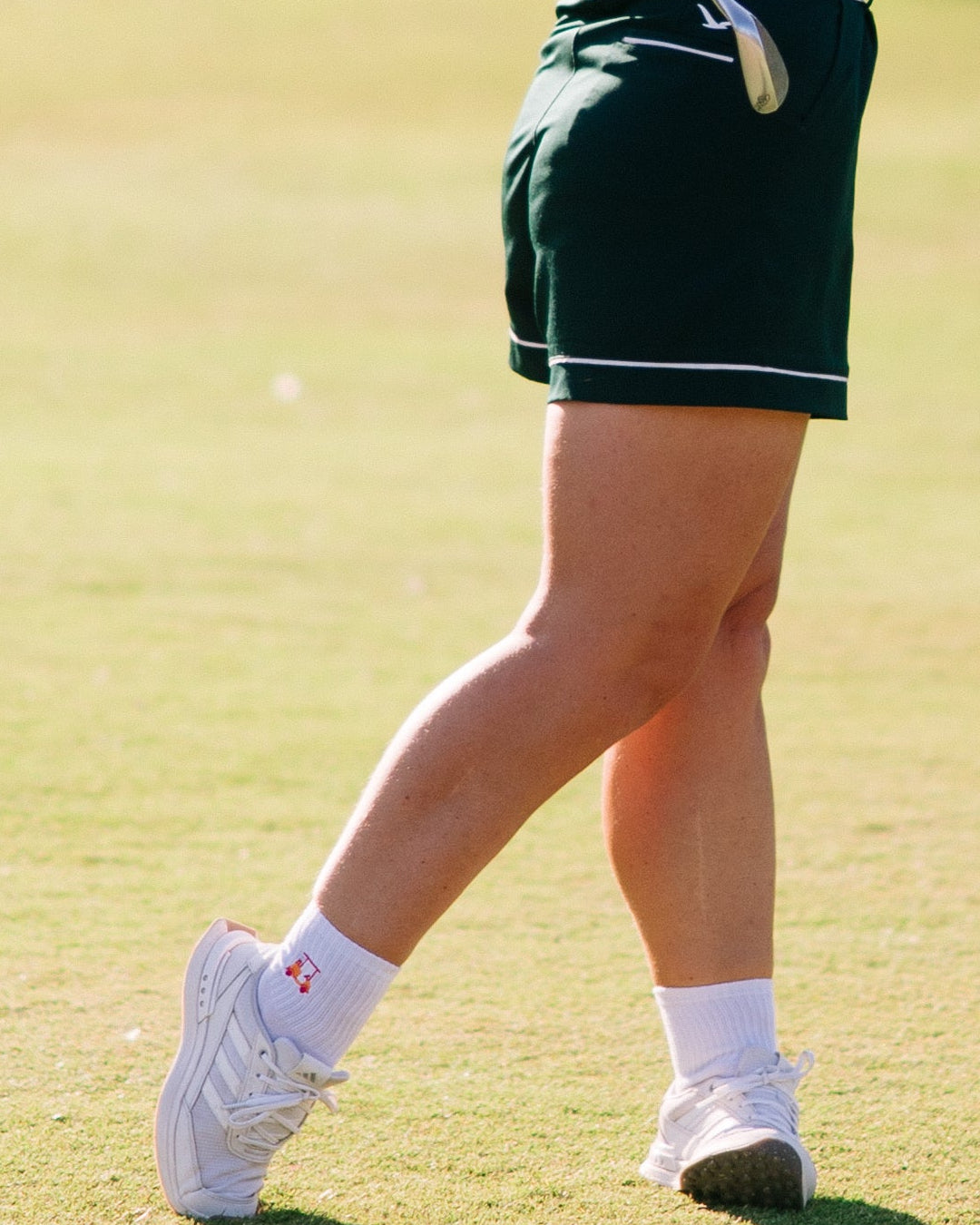 Woman playing golf on a green course with trees in the background